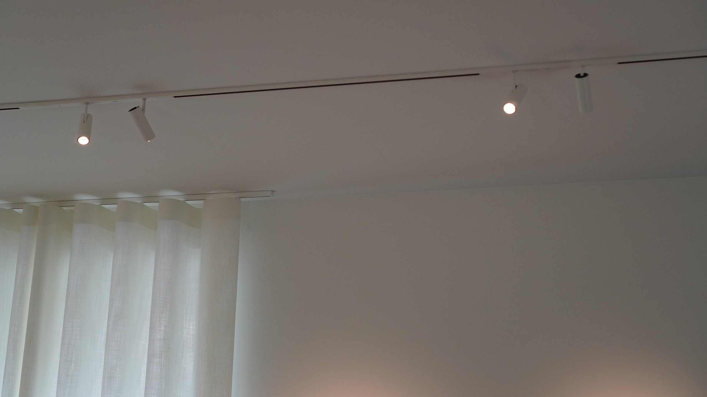 Flos Zero Track-railsysteem met richtbare Find Me-spots boven de linnen vitrage in de woonkamer