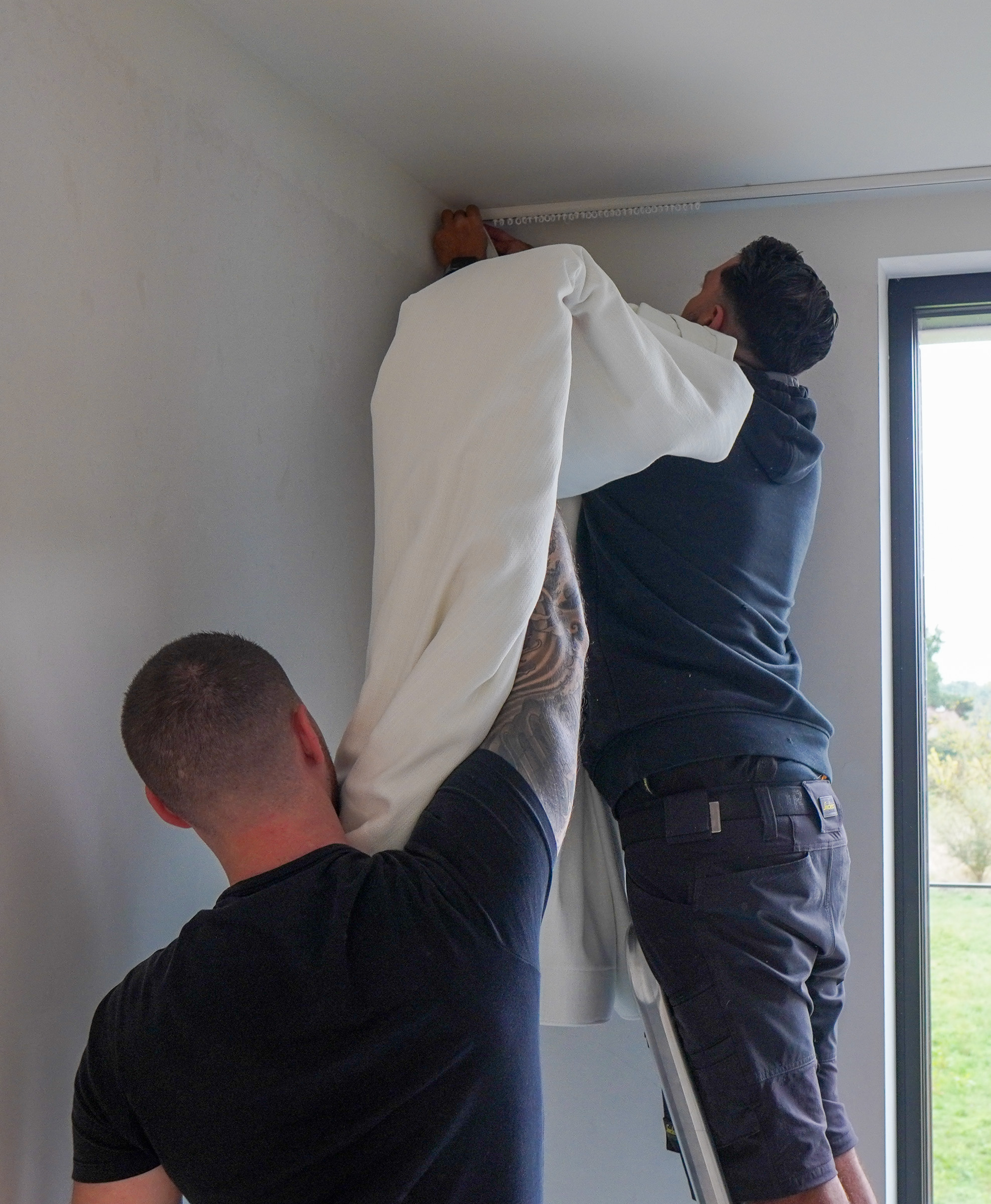 Het Loncin-team hangt de wavegordijnen in de ingewerkte plafondrail
